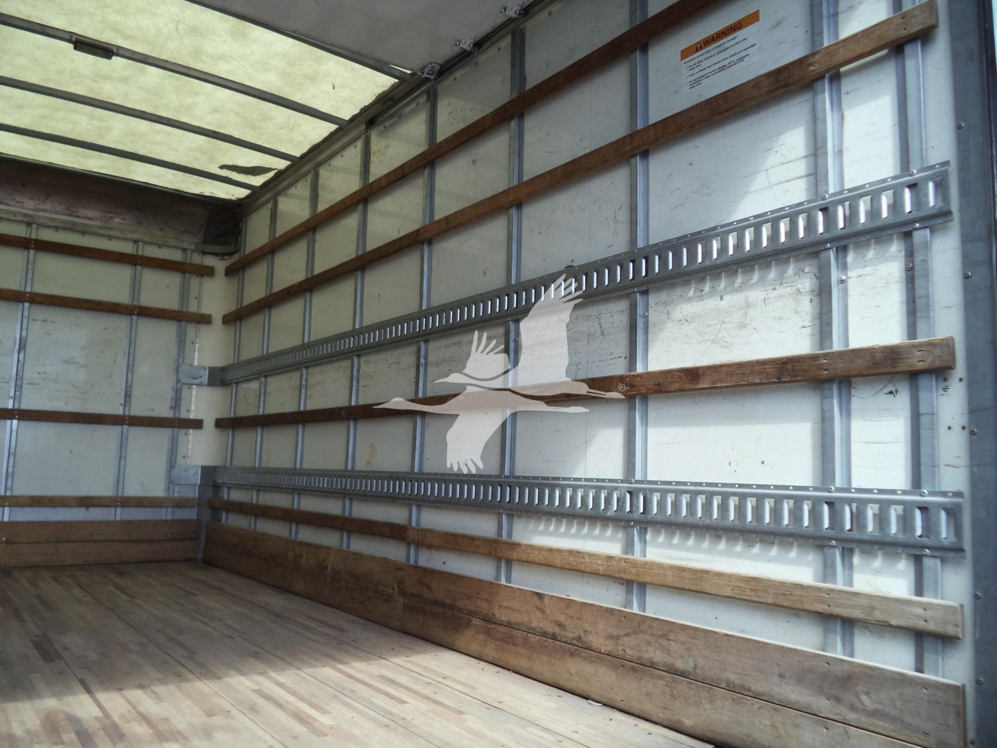 Isuzu NPR HD box truck cargo area interior showing metal side rails and wooden floor.