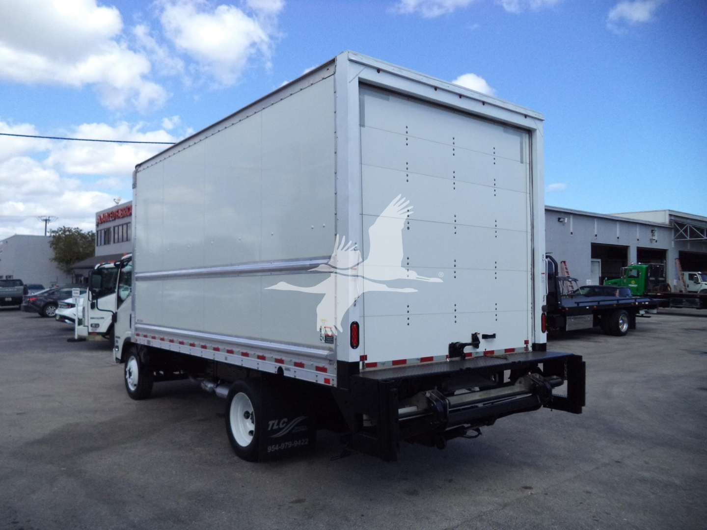 Isuzu NPR-HD box truck rear and passenger side view with large cargo box and white eagle decal on rear door.