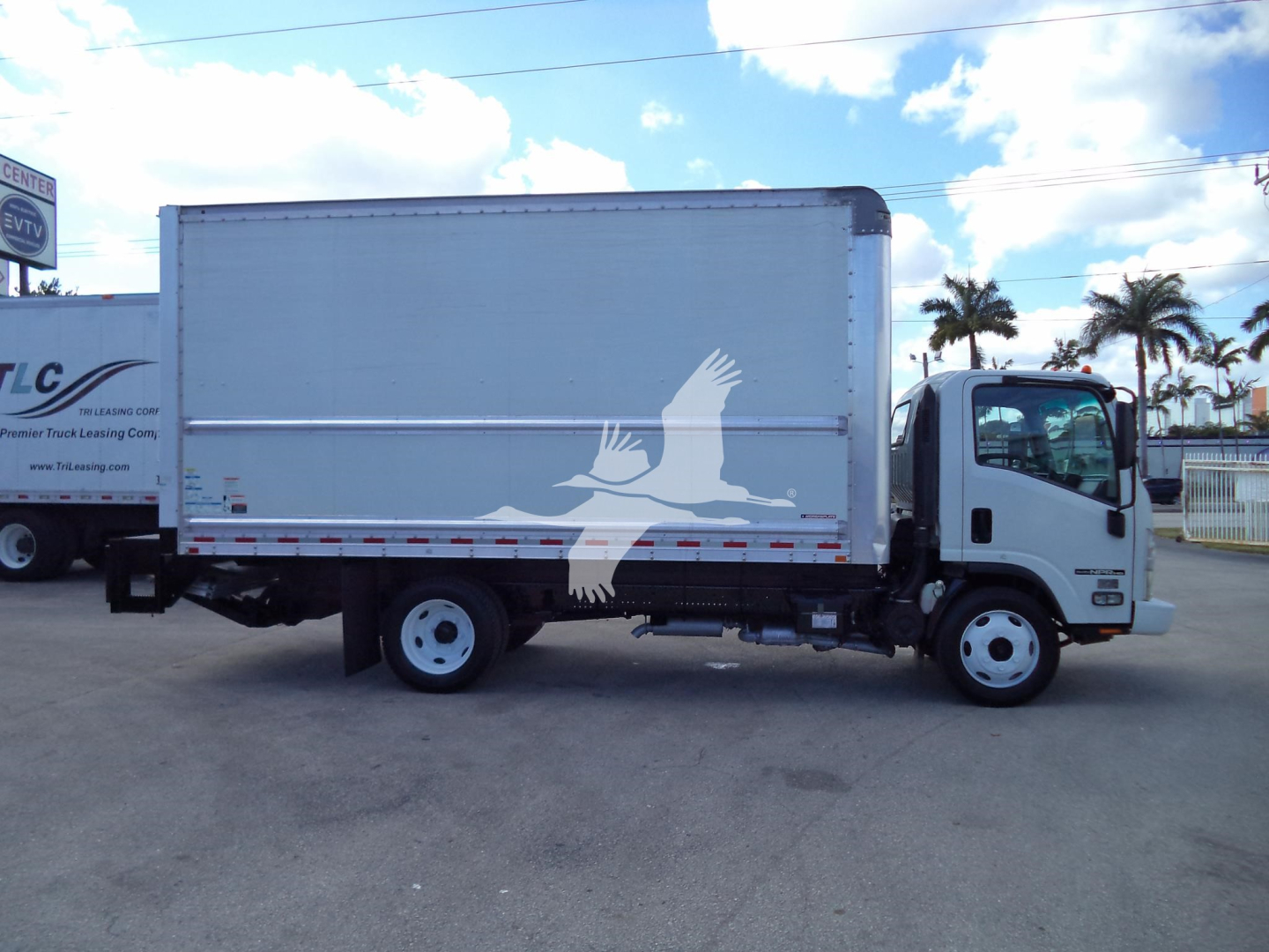 Isuzu NPR HD box truck side view showing a white cargo box with a stylized bird graphic and a cab; no legible small text visible.