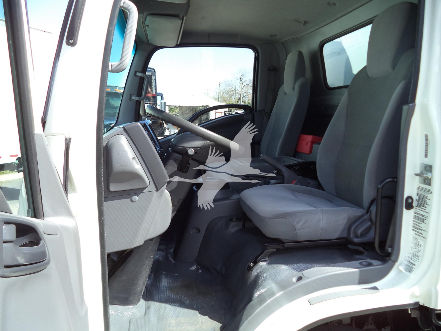 Isuzu NPR-HD truck cabin interior showing gray driver seat and dashboard from open doorway.