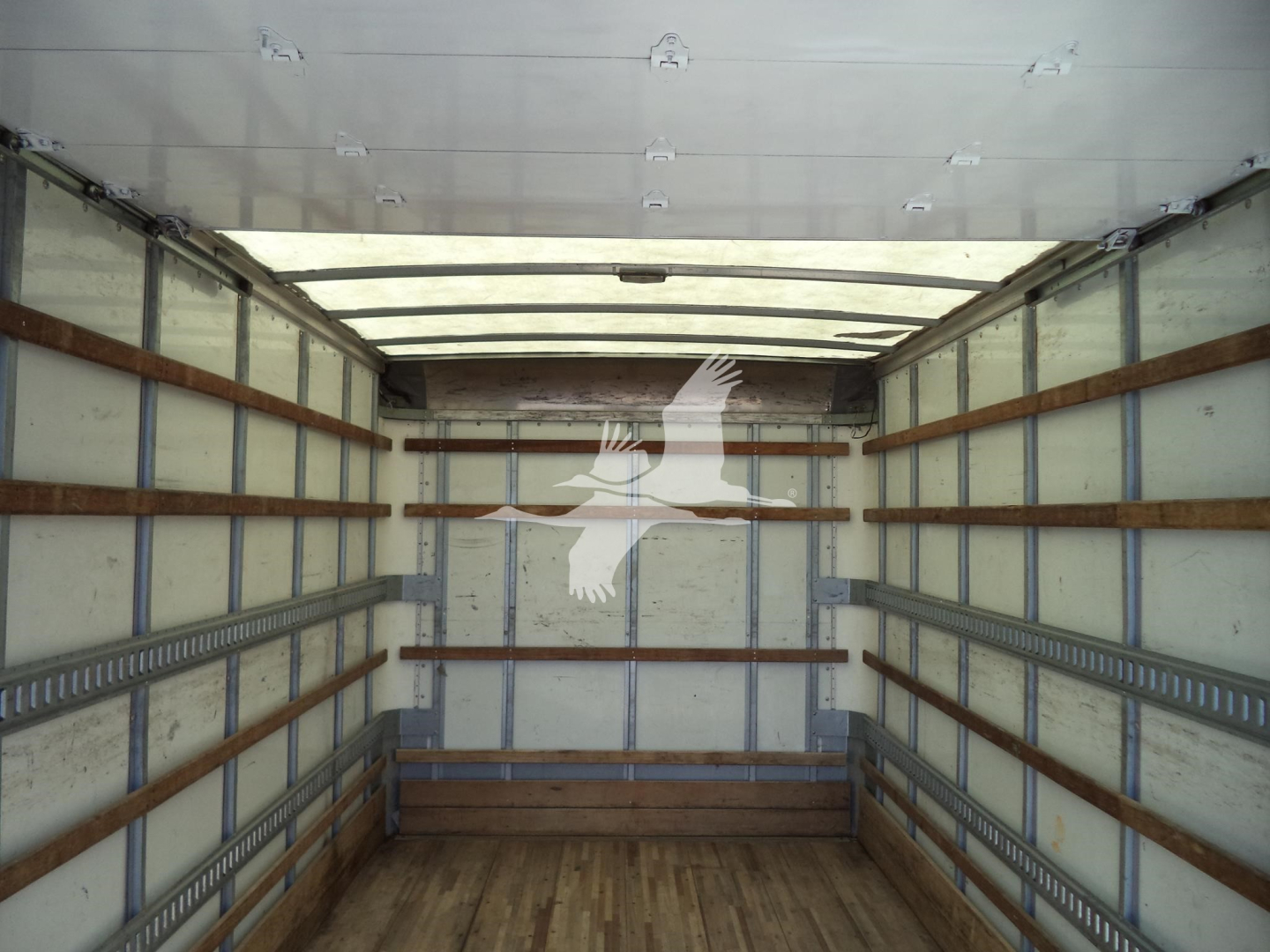 Truck cargo area interior with wooden side rails and metal wall framing. No text visible inside the box area.