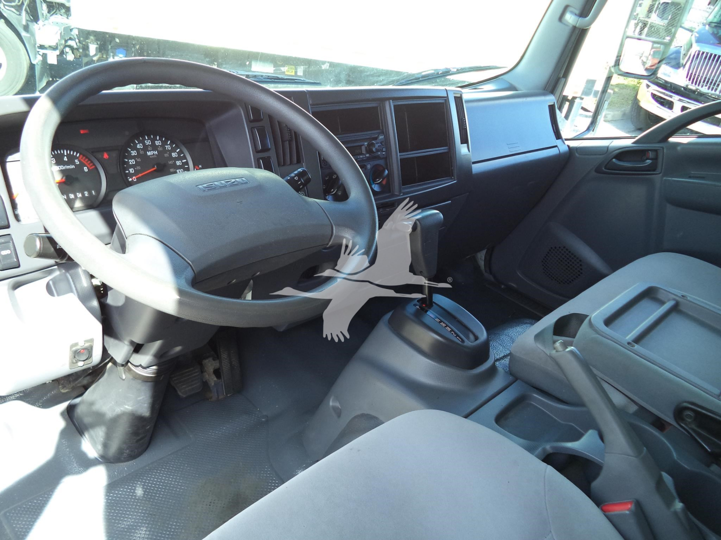 Isuzu NPR-HD truck interior showing steering wheel, dashboard, gear shifter, and front seats.