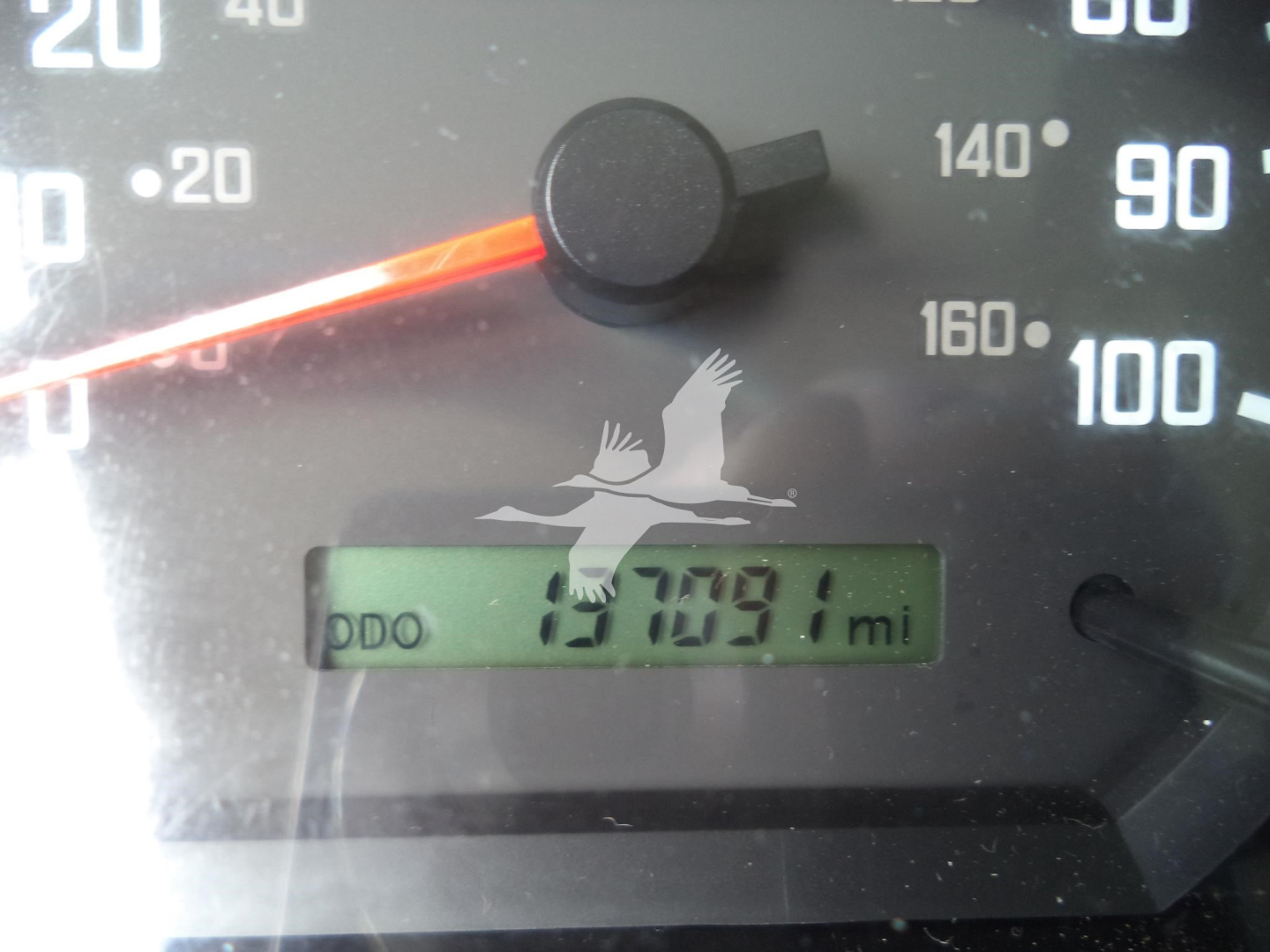 Dashboard gauge showing odometer reading and partial speedometer. Odometer reads 057091 mi. Visible text includes digits and gauge marks.