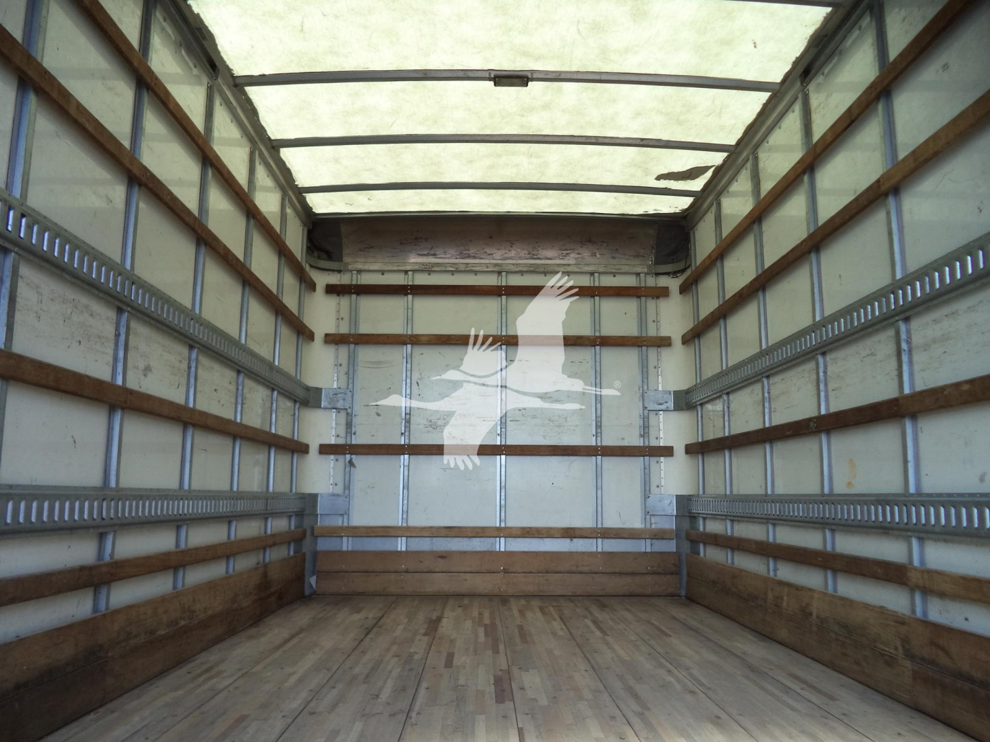 Interior cargo area of a 2020 Isuzu NPR HD box truck showing empty wooden floor and metal side rails.