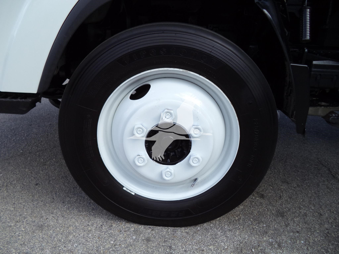 Isuzu NPR HD wheel close-up showing steel white rim with central hub and lug nuts.