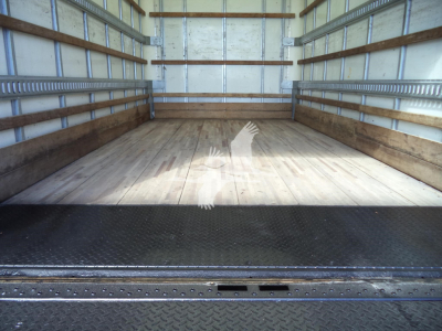 Isuzu NPR-HD box truck cargo area with wooden floor and metal sidewalls, rear entry with diamond plate threshold.