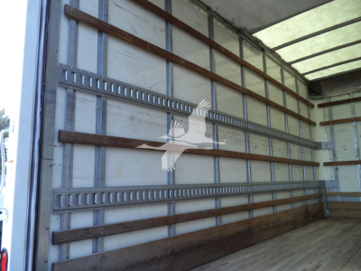 Isuzu NPR HD box truck interior cargo area with wooden and metal wall rails.