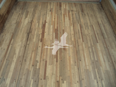 Floor of a truck box interior with wooden planks and a white bird logo on the floor.
