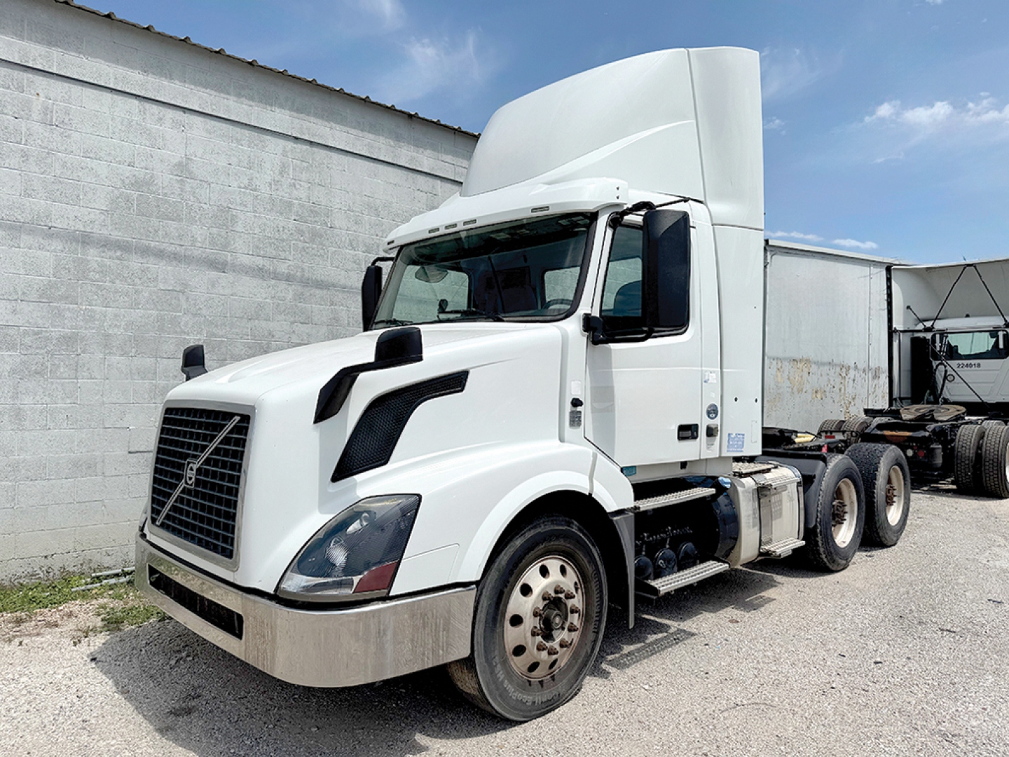 Volvo VNL 300 front-left view showing cab, hood, and front wheel; white exterior with large grille and aerodynamic mirrors.