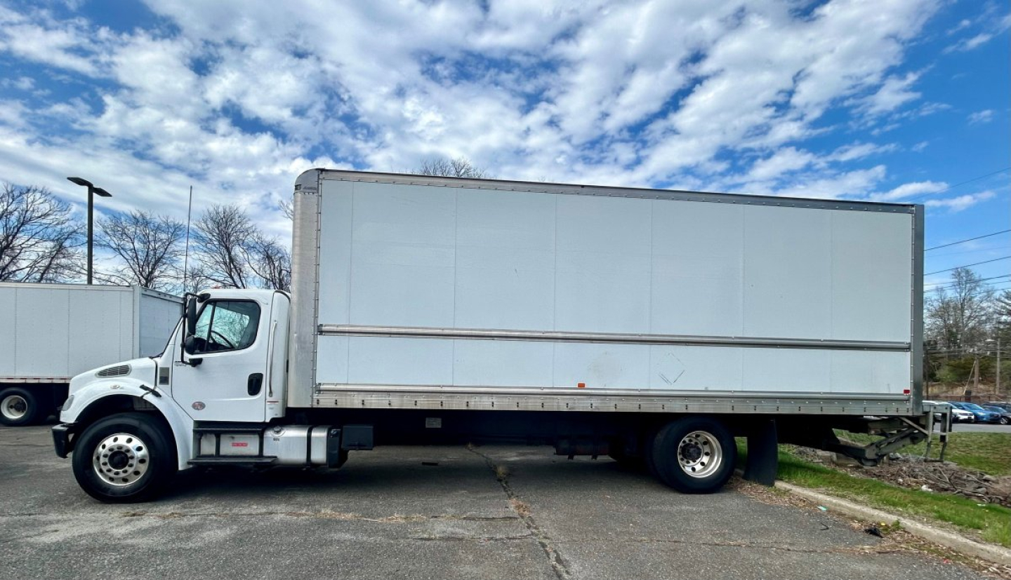 Freightliner M2 106 box truck side view showing large rectangular cargo box and cab with white paint