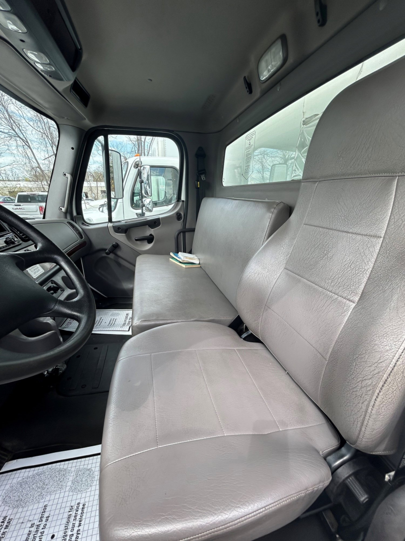 Truck cab interior of a 2019 Freightliner M2 106 showing front bench seat and driver side with steering wheel and dashboard.