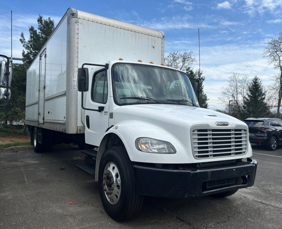 Truck side/front view of a white 2019 Freightliner M2 106 medium-duty box truck with a large box cargo area, dual rear wheels, and black front bumper.