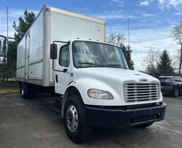 Truck side/front view of a white 2019 Freightliner M2 106 medium-duty box truck with a large box cargo area, dual rear wheels, and black front bumper.