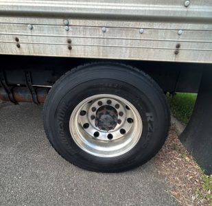 Wheel and fender area of a Freightliner M2 106 MEDIUM D truck showing a front wheel with black tire and silver steel rim
