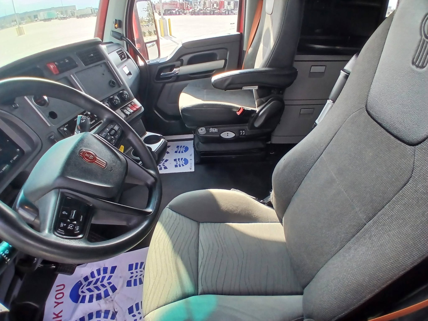 Kenworth T680 truck interior driver seat and dashboard view with steering wheel and center console.