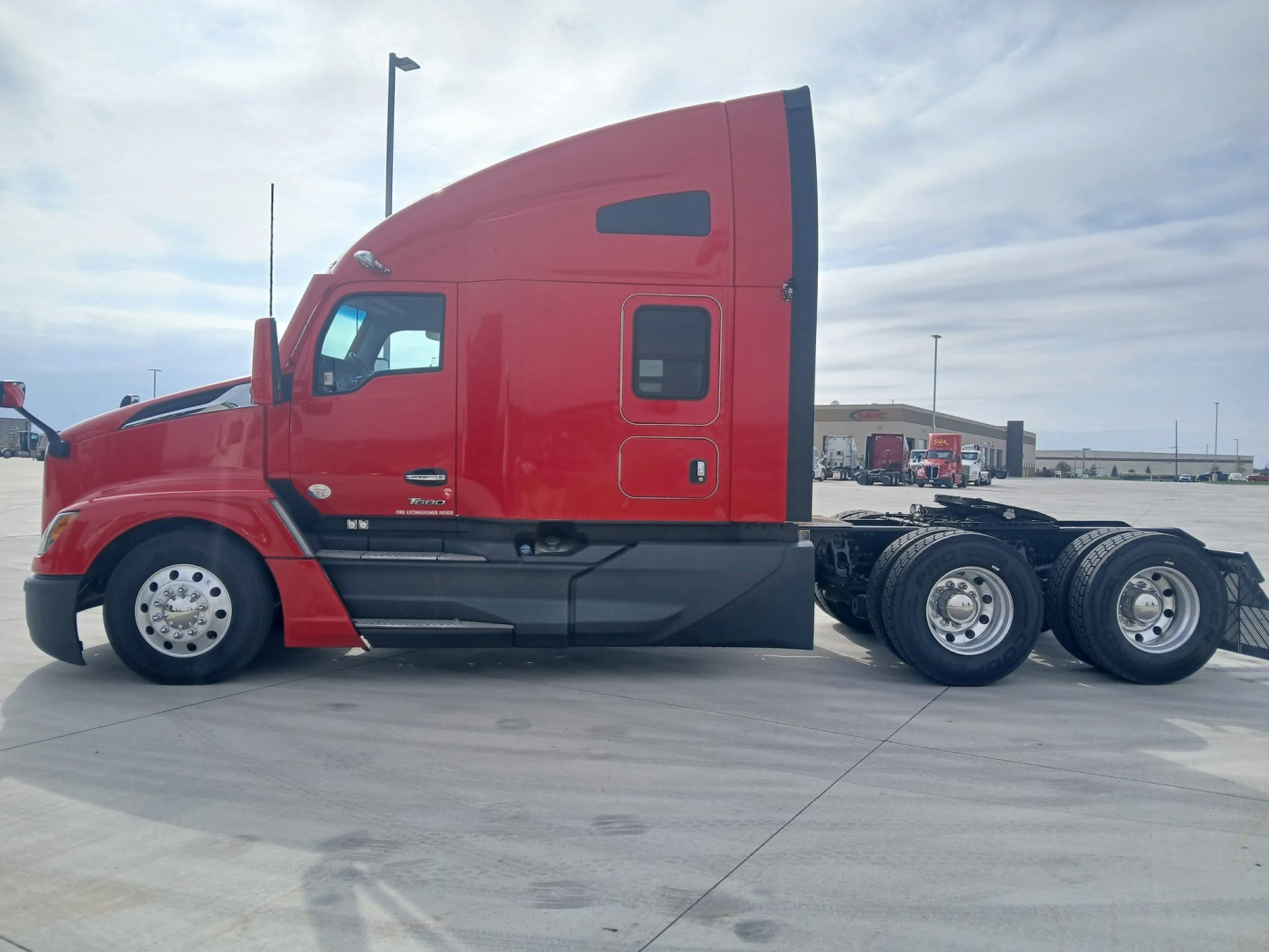 Kenworth T680 sleeper cab side view showing red exterior, two fuel tanks, and six-wheel rear configuration.