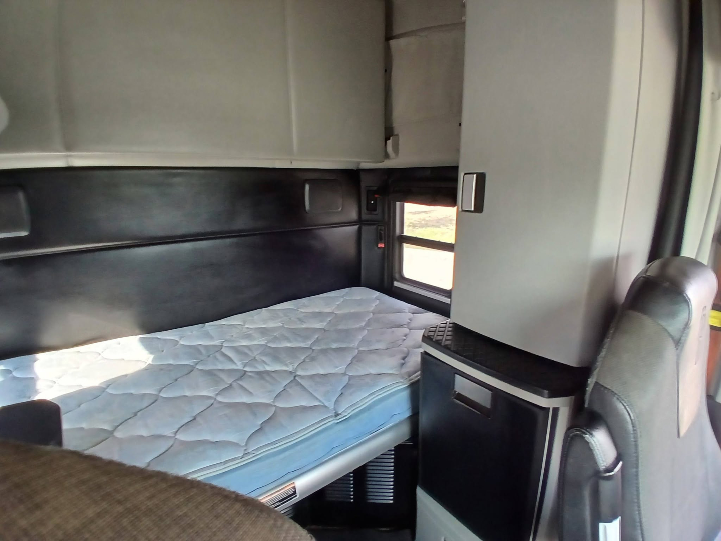 Kenworth T680 sleeper cab interior with bunk bed and storage cabinet visible