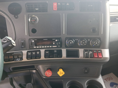 Dashboard of a Kenworth T680 truck showing various controls, gauges, and two colored knobs (red and yellow) with surrounding switches.