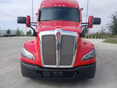 Kenworth T680 front view showing bold chrome grille with Kenworth emblem, red cab, black bumper, and large side mirrors.