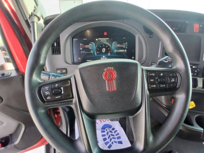 Steering wheel and dashboard interior of a Kenworth truck with digital instrument cluster visible.