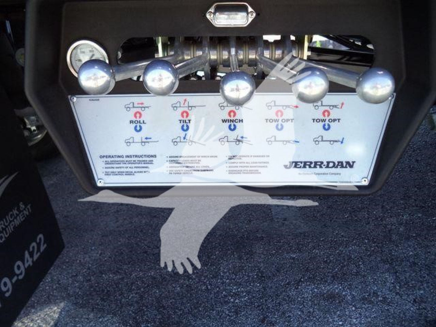 Truck rollback control panel with multiple toggles and levers labeled Roll, Tilt, Winch, Tow Opt, Jerr-Dan branding.