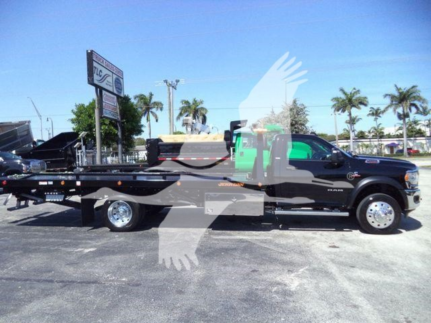 Ram 5500 SLT truck with a rollback flatbed, side view showing extended wheelbase and tow setup.