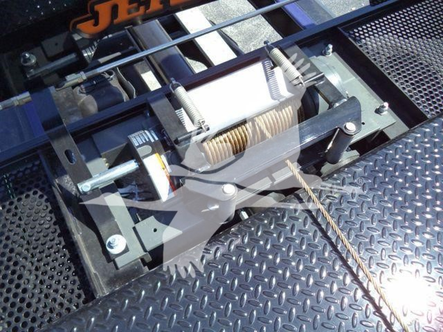Winch assembly with steel cable mounted on a Ram 5500 rollback truck, showing a compact electric winch and roller fairlead on a diamond plate bed.