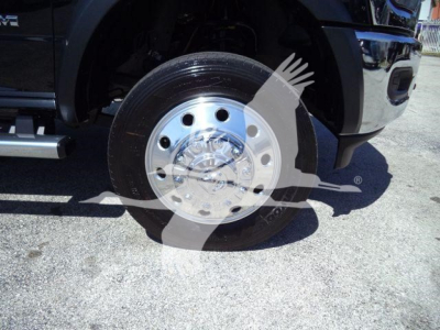 Truck front wheel with chrome hub and black tire, partial front bumper; watermark overlays the image.