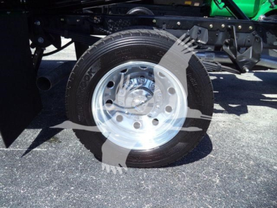 Truck rear wheel assembly with metal rim and black tire; undercarriage frame and suspension components visible.