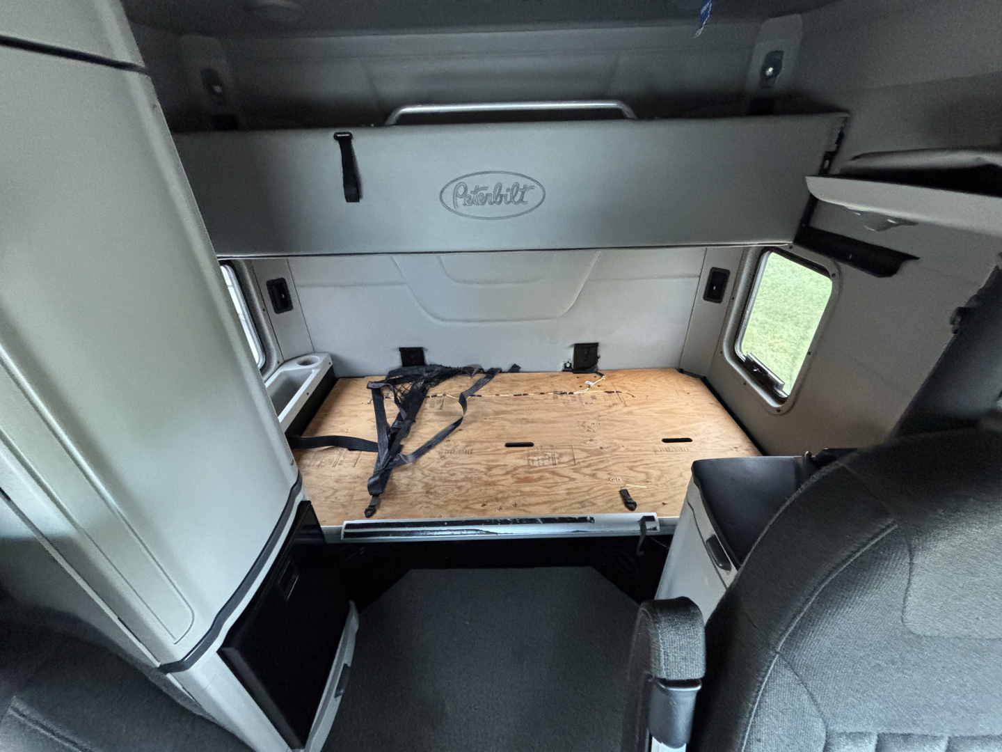 Peterbilt 579 cab interior showing sleeper area with Hasio storage drawer and wooden floor panel in cargo area.