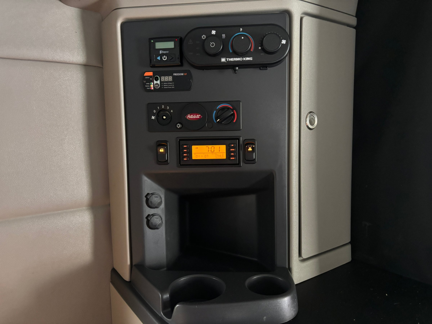 Peterbilt 579 center console area showing climate controls, radio, and power outlets with orange digital display.