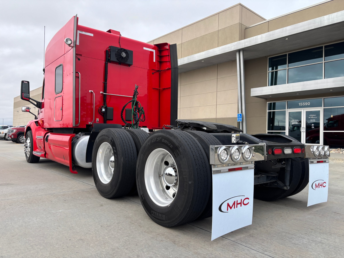 Peterbilt 579 tractor in red, rear view showing dual rear axle, chrome wheels, mud flaps, and fifth wheel hitch.