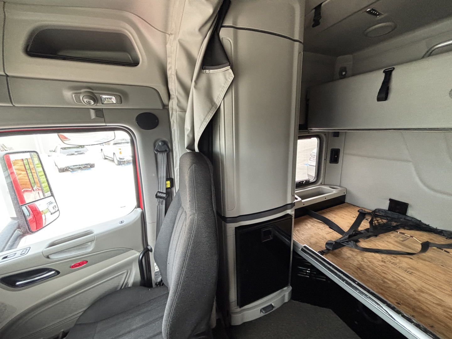 Peterbilt 579 sleeper cab interior showing bunk area and driver's seat with overhead storage and window view.
