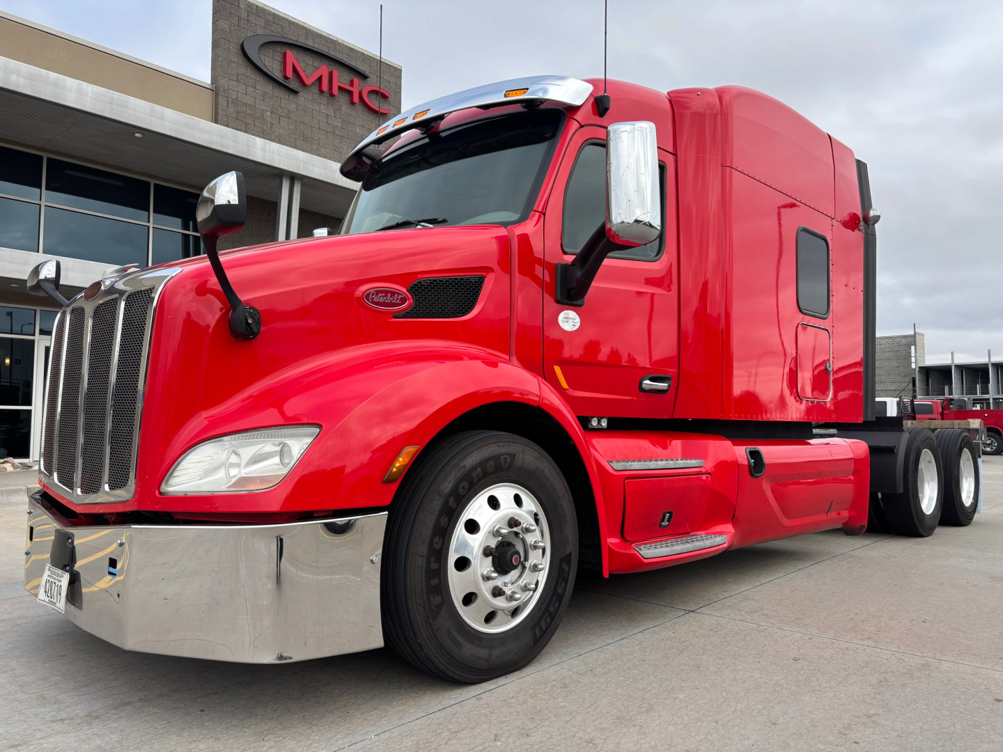 Peterbilt 579 tractor ends with red exterior, front chrome bumper, large grille, side mirrors, and sleeper cab. visible text on truck includes Peterbilt logo on grille and side steps.
