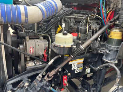 Peterbilt 579 engine bay showing air intake hoses, brake fluid reservoir, and various engine components.