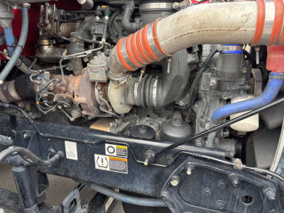 Peterbilt 579 engine bay with large intake hoses and turbocharger visible, showing radiator support and various hoses and components.