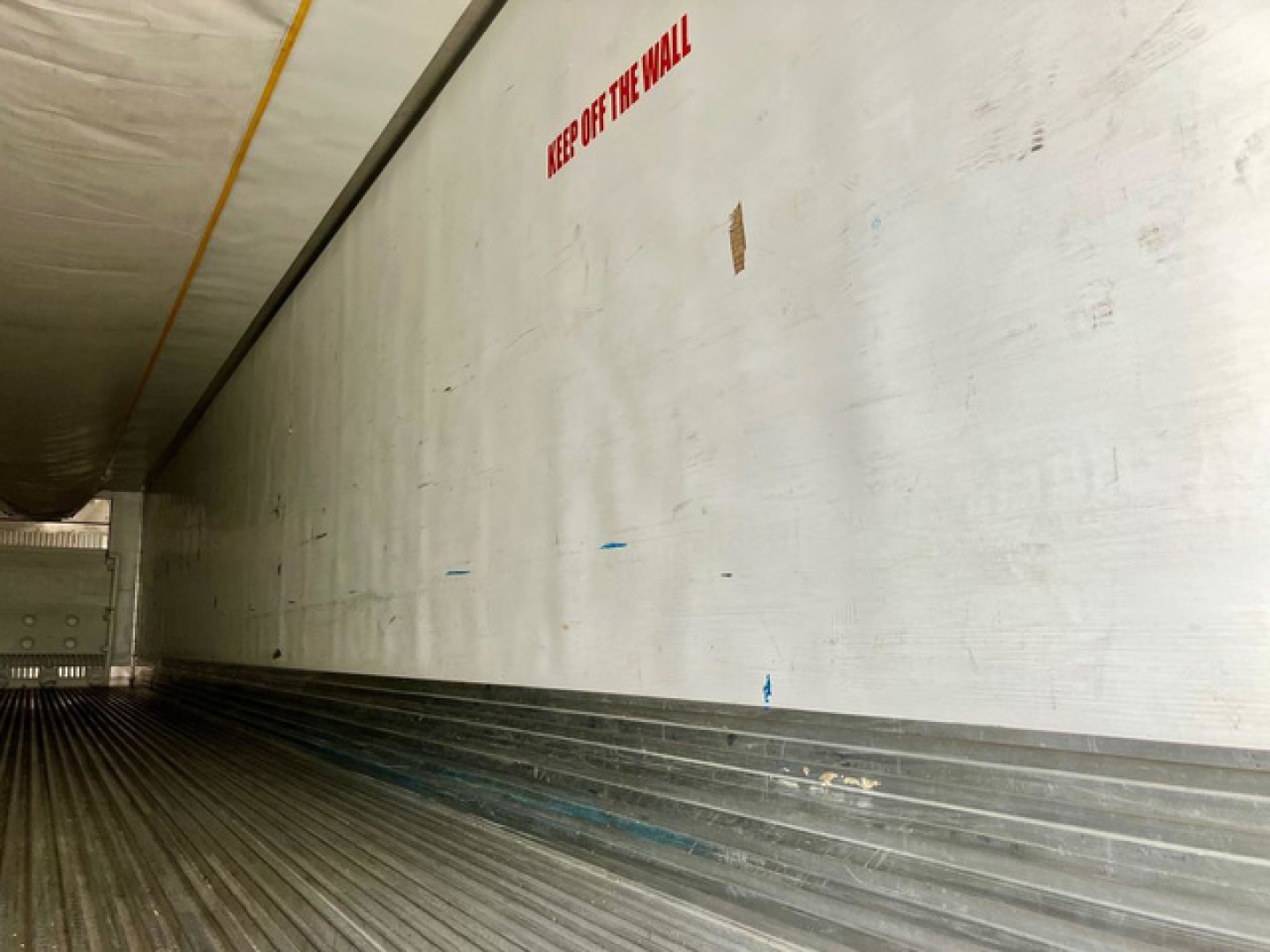Trailer interior wall with ribbed floor and a small red warning text.”