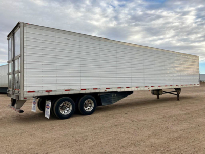 Trailer side view showing a refrigerated utility trailer with tandem axles and doors at rear, silver exterior, stock number U90715.
