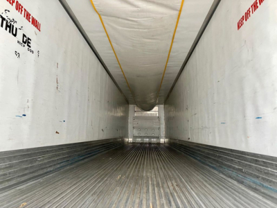 Trailer interior view into a 2020 utility reefer cargo trailer with ribbed aluminum floor and white walls, yellow ceiling stripe, and rear doors visible at far end.