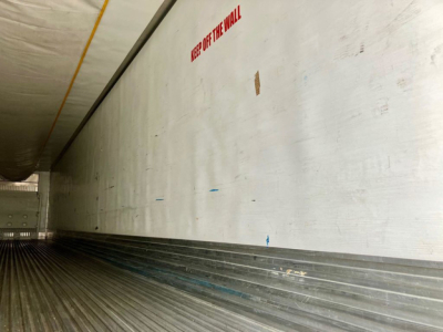 Trailer interior wall with ribbed floor and a small red warning text.”