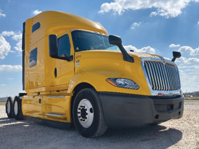 Truck cab with bright yellow International LT Series sleeper in a three-quarter front view showing front grille, headlights, and side mirrors.
