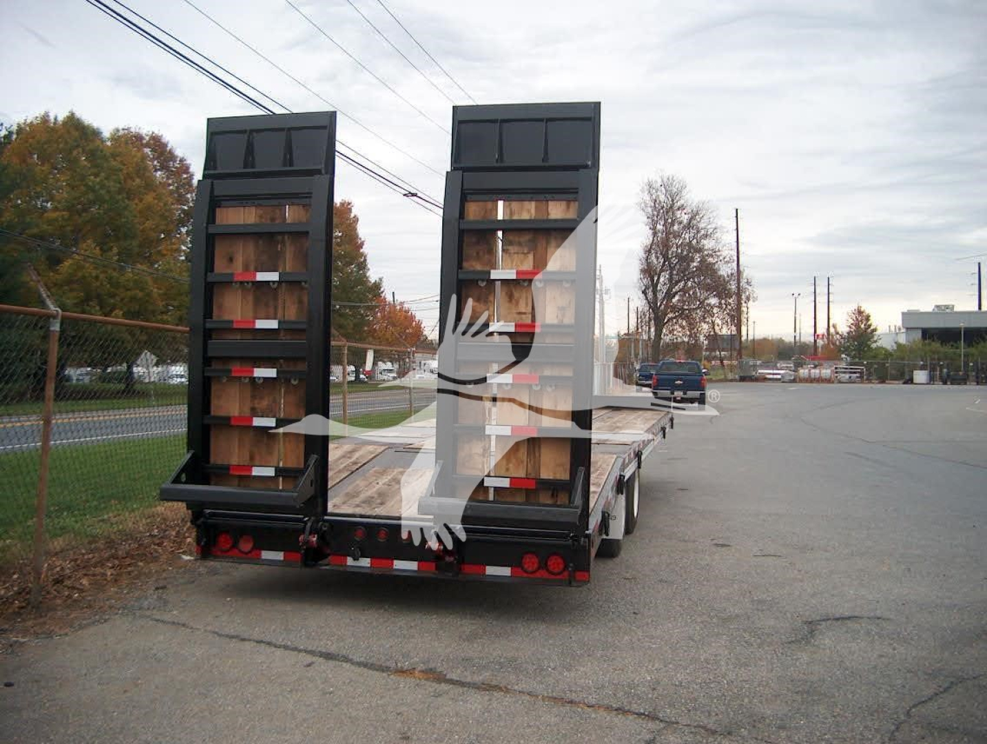 Trailer showing dual ramps at rear with wooden deck and black metal ramp gates.