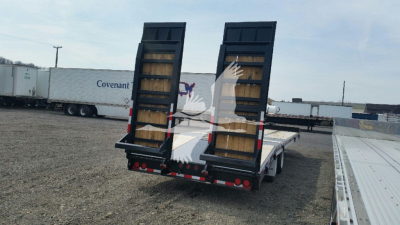 Flatbed trailer with rear ramps up, black frame and wooden deck, tires, and reflective lights visible.