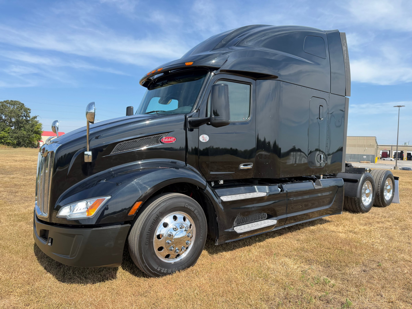 Peterbilt 579 truck in black, semi-truck cab with sleeper, front left view showing chrome fuel tanks and dual rear axles.