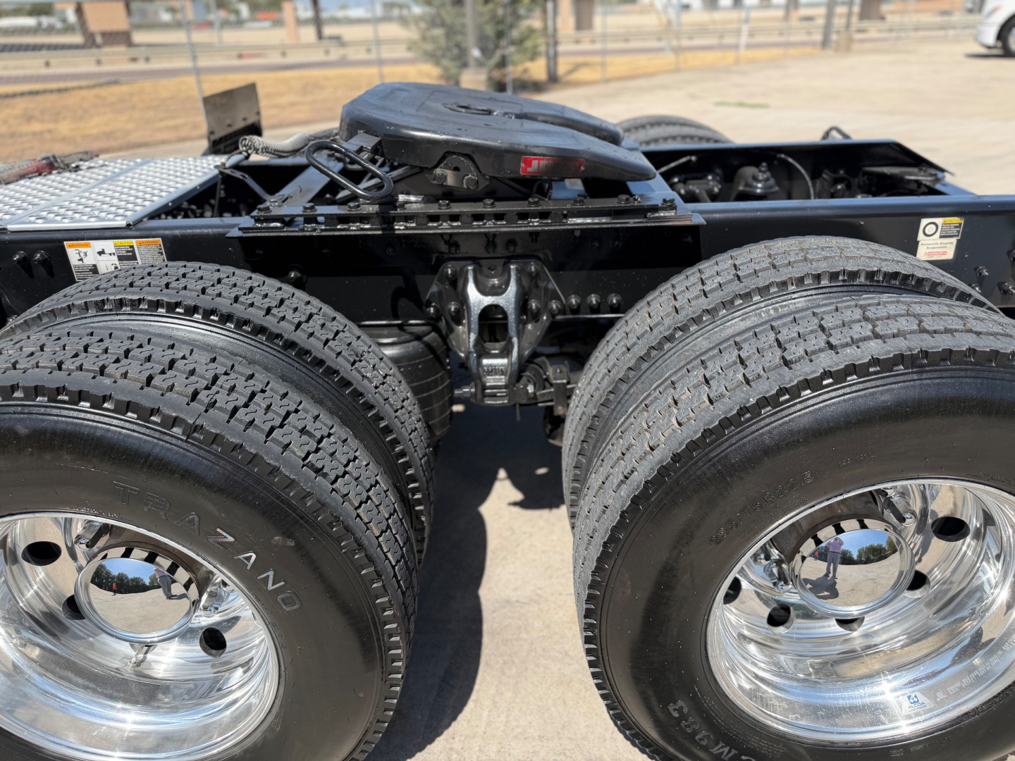 Kenworth T880 chassis showing dual rear axles and tires with chrome rims, undercarriage visible, front area cropping shows fifth wheel and frame rails.