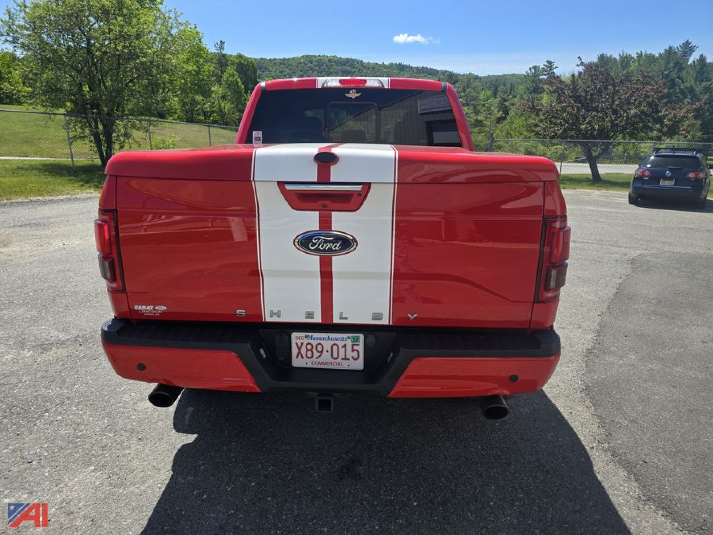 Rear view of a red 2016 Ford Shelby F150 Crew Cab with white racing stripe, showing tailgate badges and Ford emblem.