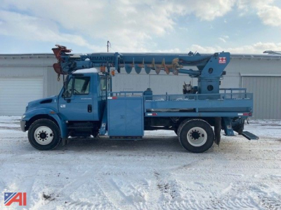 Truck mounted crane: blue 2002 International DuraStar 4300 digger, side view with boom extended, Derrick/Crane equipment on bed, in snow.