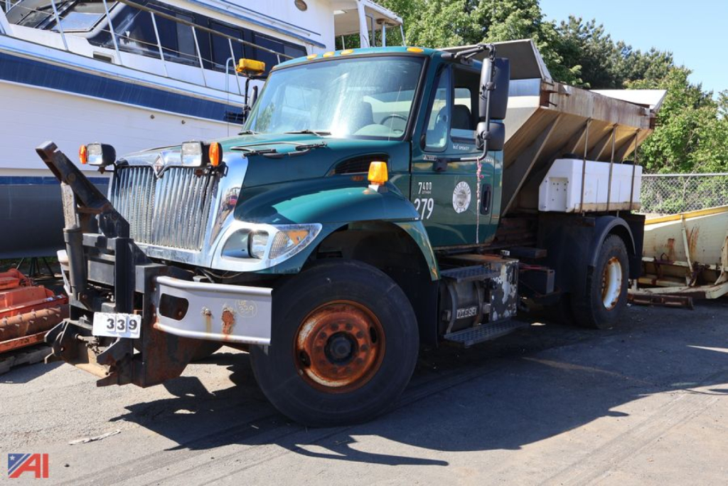 International WorkStar 7400 plow truck with green cab and orange wheels, dumping bed, side mirror, and plow apparatus visible