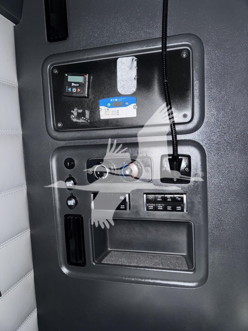Dash console with control panel and wiring in Freightliner Cascadia interior; visible labels include a small blue-and-white sticker and switches.