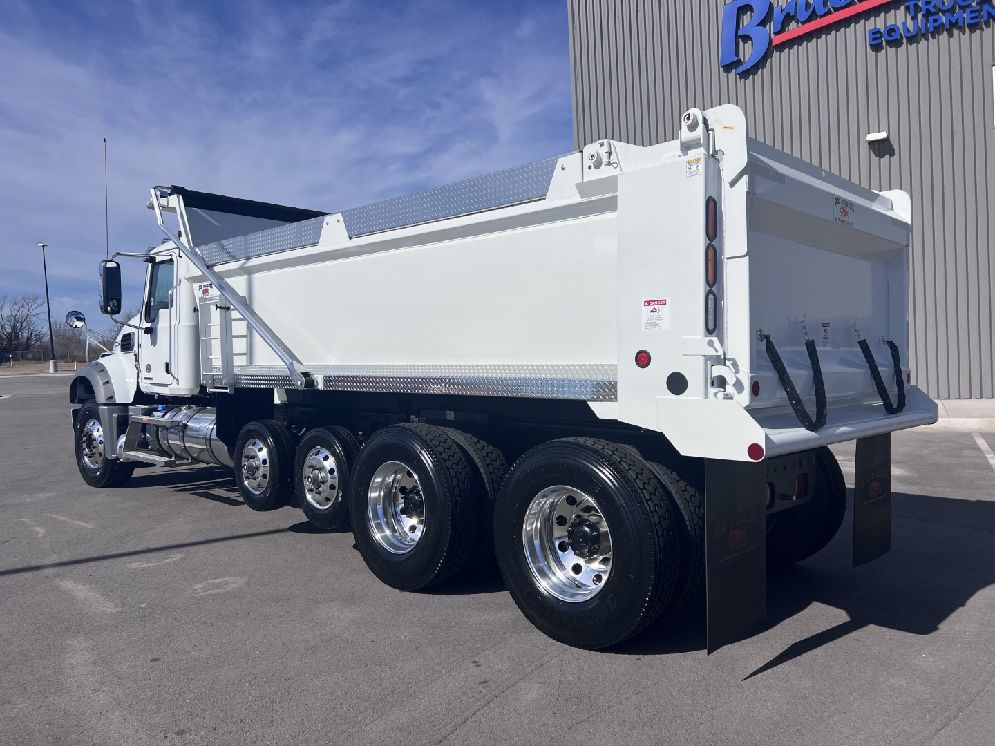 Dump truck rear three-quarter view showing dual rear axles and large cargo bed on a 2026 Mack GR64F.